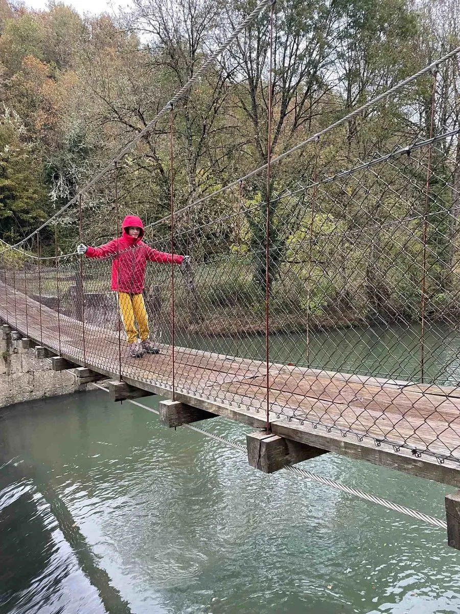Puente colgante de Aribe durante nuestra visita familiar, con tablones y cables sobre el río