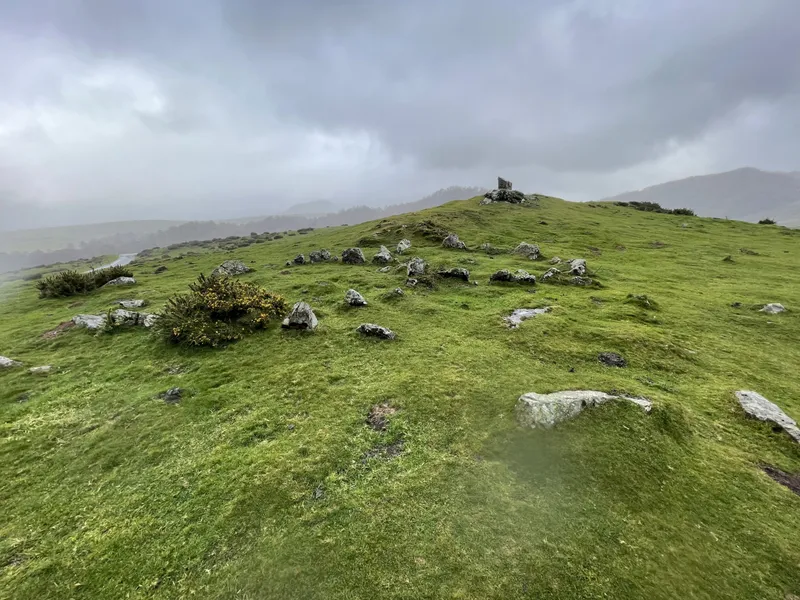 Piedras de Azpegi sobre una pradera con montañas y niebla al fondo