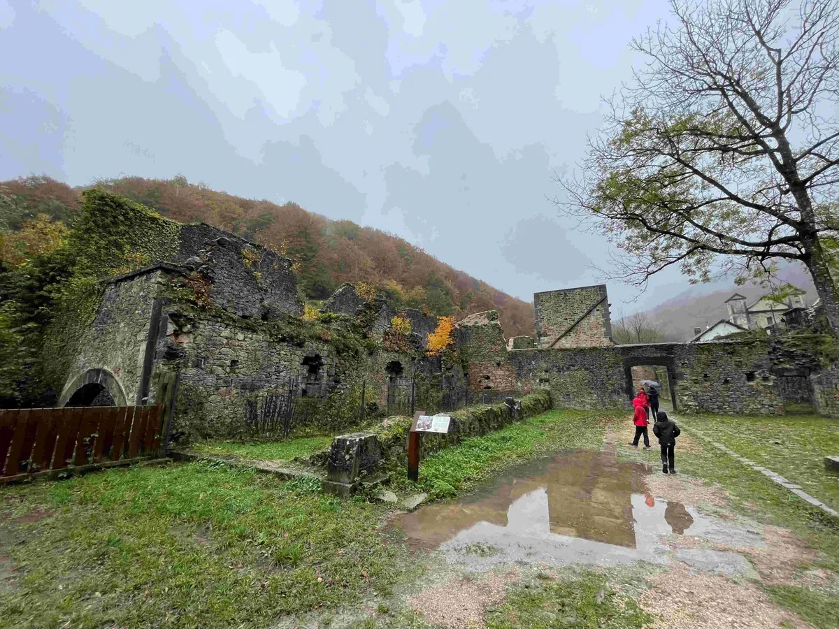 Recinto de la antigua fábrica de armas de Orbaizeta con muros de piedra y charcos